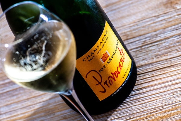 A bottle of champagne next to a glass of wineDescription automatically generated