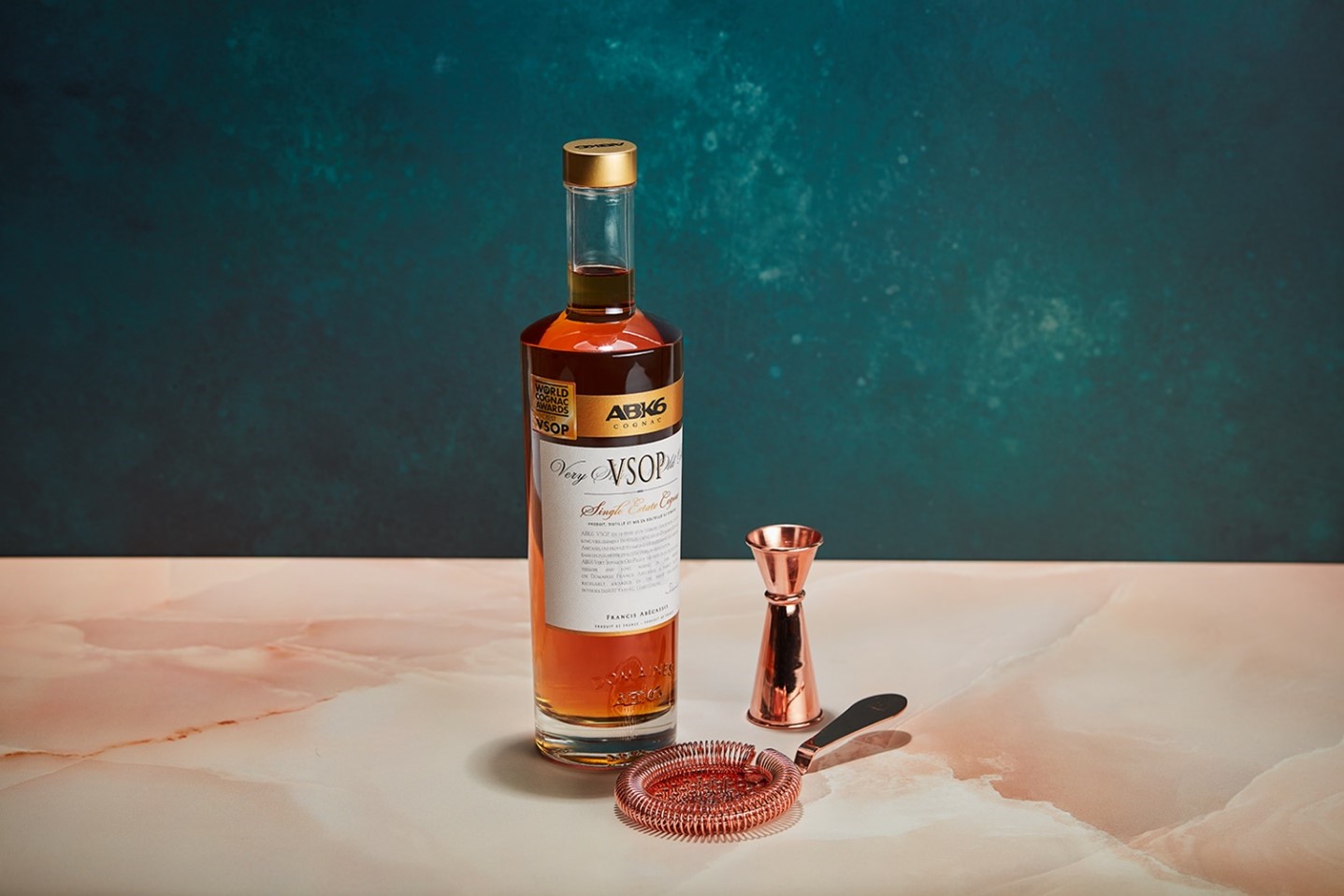 A bottle of alcohol next to a measuring cupDescription automatically generated
